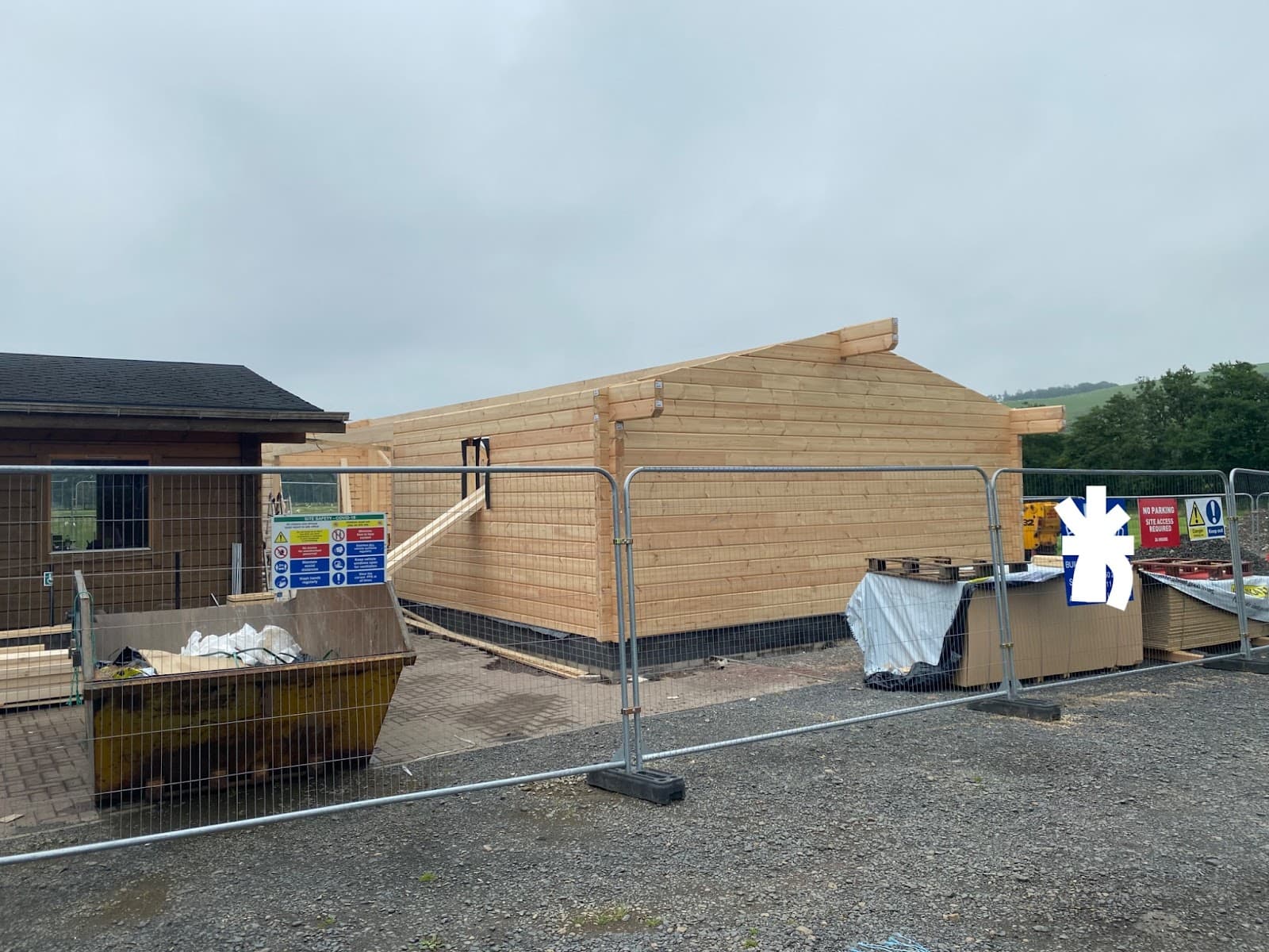 Part-built cafe exterior behind safety fencing and material stacks.